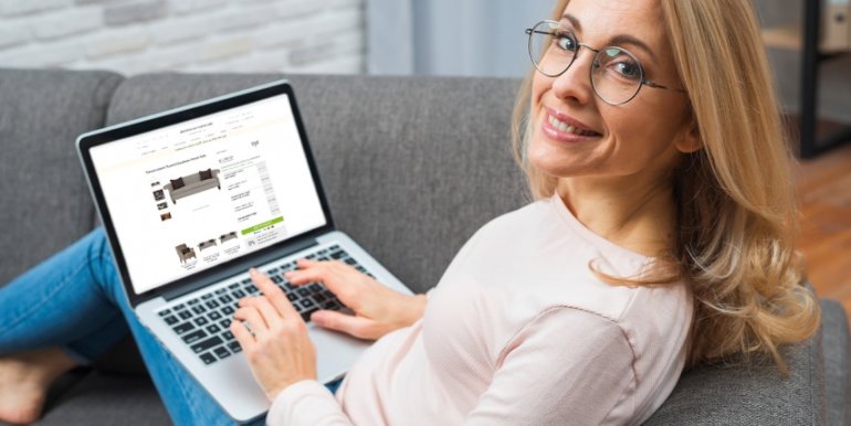 Smiling woman sitting on a sofa using a laptop for online shopping