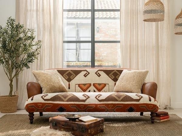 Boho patterned sofa with leather arms and textured cushions in a bright neutral living room.