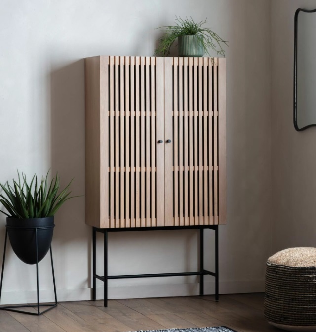 Styled interior view of the Gallery Direct Okayama 2 Door Cocktail Cabinet with oak slatted doors and sleek black base