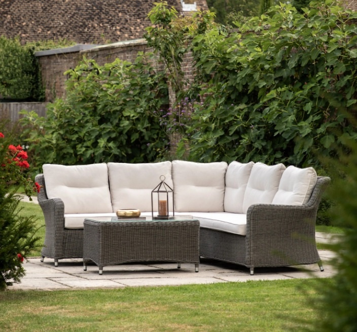 Luxury Windsor corner garden furniture set styled on a modern stone patio, showing the weatherproof PE wicker and plush neutr