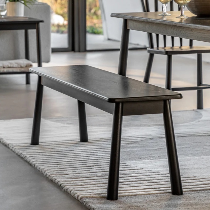 Gallery Direct Wycombe Balck Dining Bench next to a dining table on a cream rug