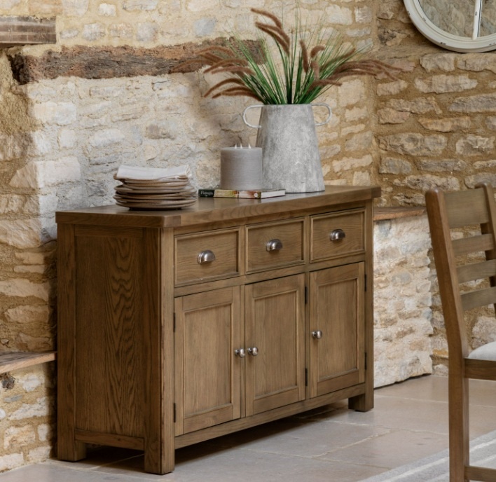 Gallery Direct Hardwick 3 Door 3 Drawer Sideboard in kitchen with tiled floor and aged stone wall