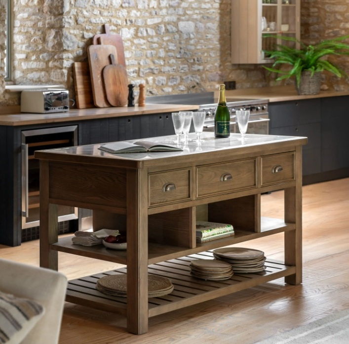 Gallery Direct Hardwick Kitchen Island in kitchen with wooden floor and stone cottage walls with bottle of champagne on top