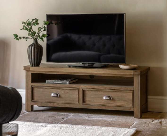 Gallery Direct Hardwick Media Unit with tv on top and vase on carpet in lounge in front of blue sofa