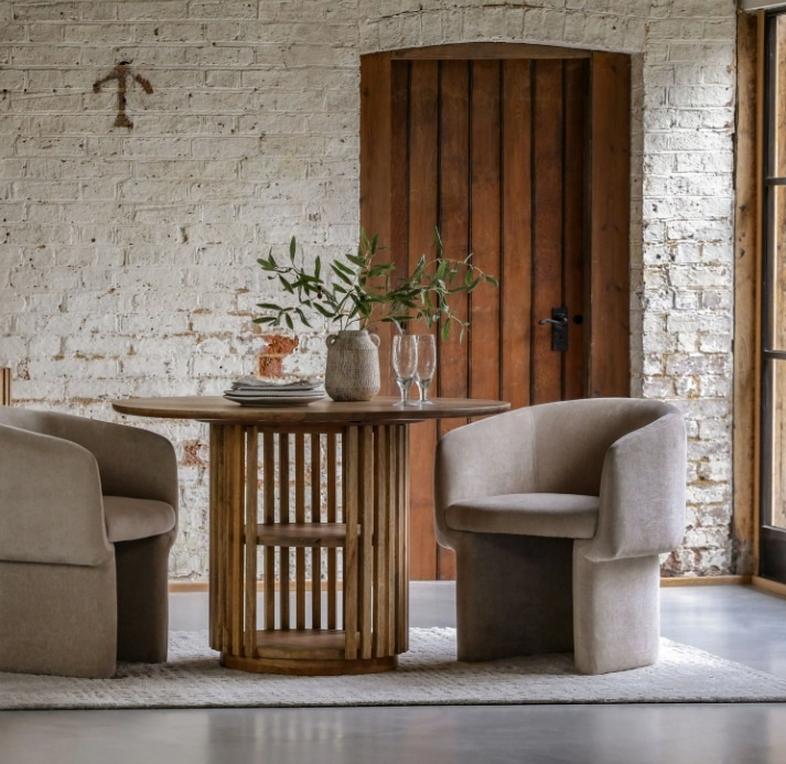 Gallery Direct Voss Dining Table between two chairs in a room with whitewashed brick walls