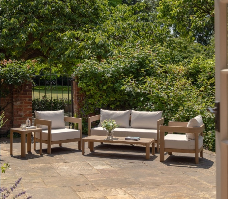 Modern Madeira garden sofa set styled on a stone patio with outdoor accessories and greenery.