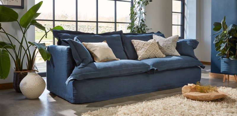 Tetrad Ava Midi Sofa in denim blue linen with slouchy feather cushions in a bright, modern living room with indoor plants - B