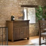 Gallery Direct Hardwick Oak 2-Door 1-Drawer Sideboard in a rustic room setting with stone walls and a window