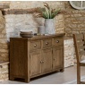 Gallery Direct Hardwick 3 Door 3 Drawer Sideboard in kitchen with tiled floor and aged stone wall