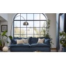Industrial loft style living area featuring a slouchy Tetrad Ava Midi Sofa in blue loose cover fabric against a large arched 